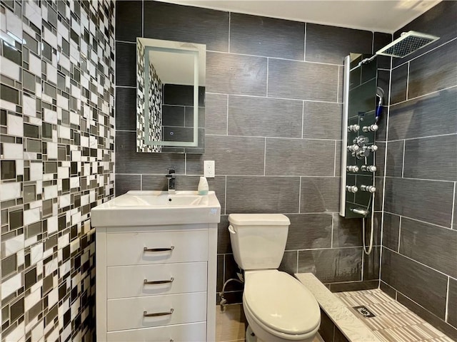 bathroom featuring toilet, a tile shower, tile walls, and vanity