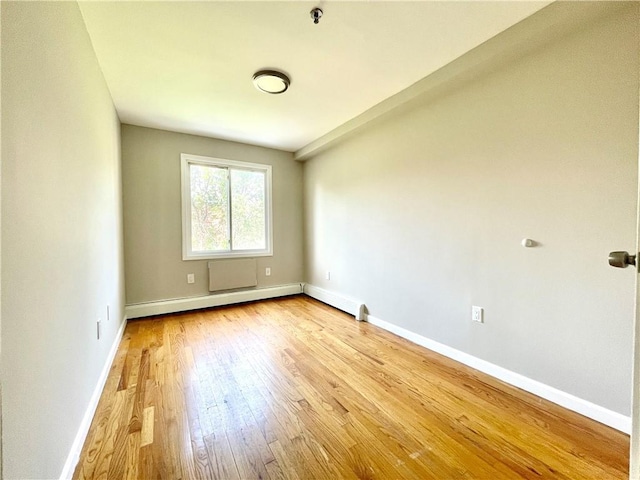 spare room featuring light wood-type flooring, baseboard heating, and baseboards