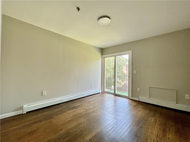 spare room featuring a baseboard radiator, baseboards, and dark wood finished floors