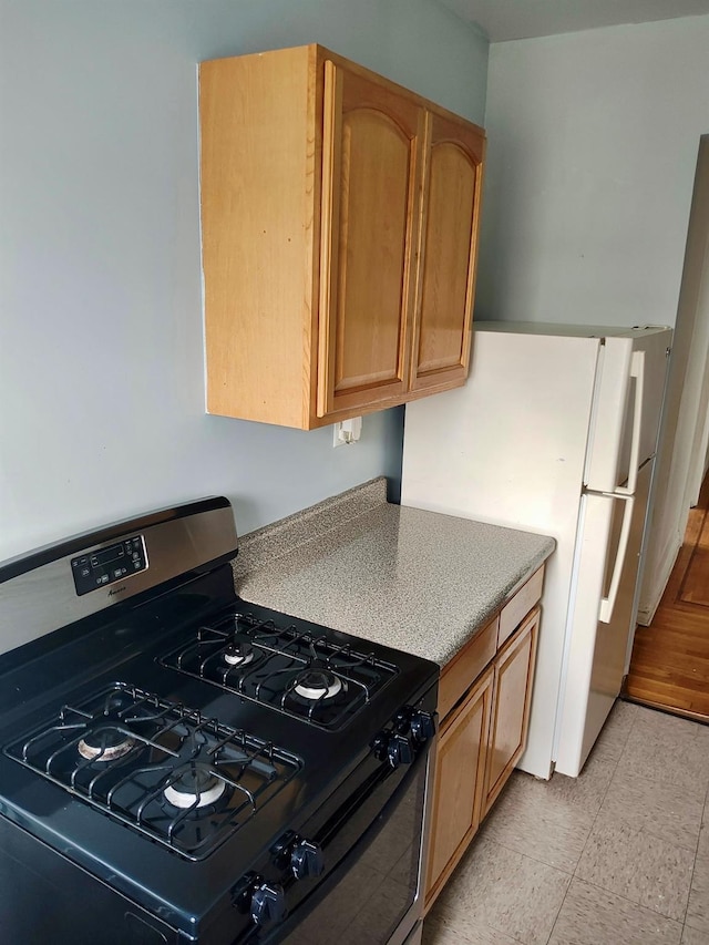 kitchen with light countertops, gas stove, and freestanding refrigerator