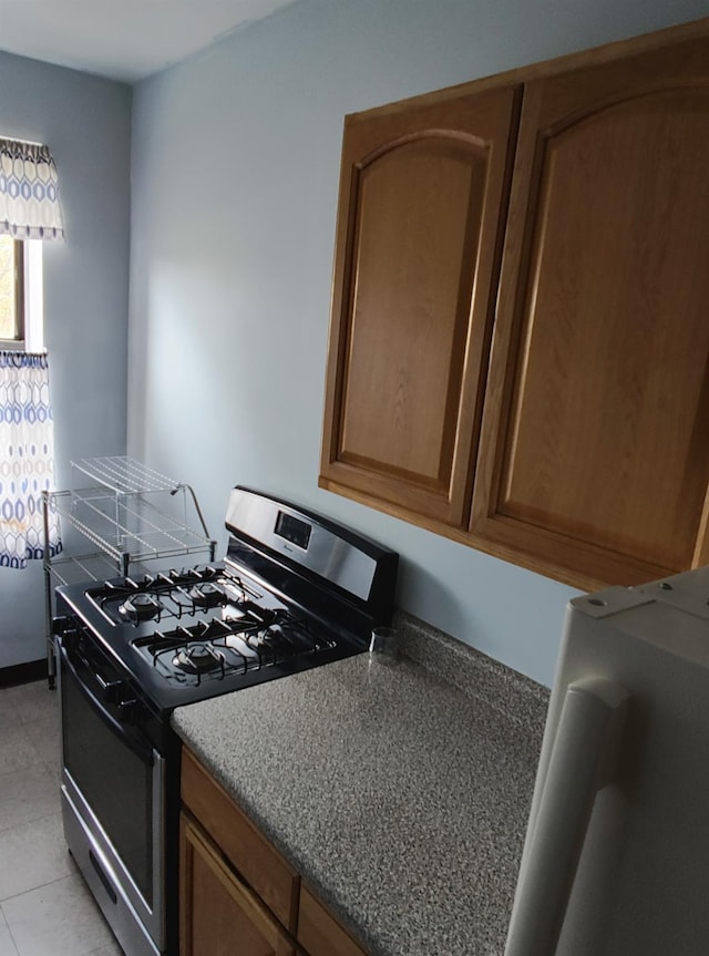 kitchen featuring light tile patterned floors, brown cabinets, and stainless steel range with gas stovetop