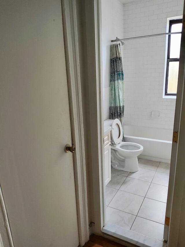 bathroom featuring tile patterned flooring, bathing tub / shower combination, and toilet