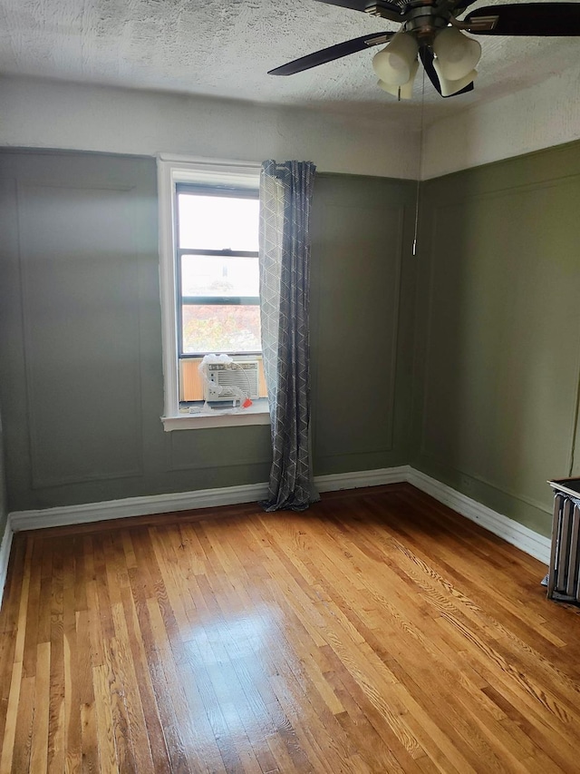 empty room with light wood finished floors, baseboards, and a textured ceiling