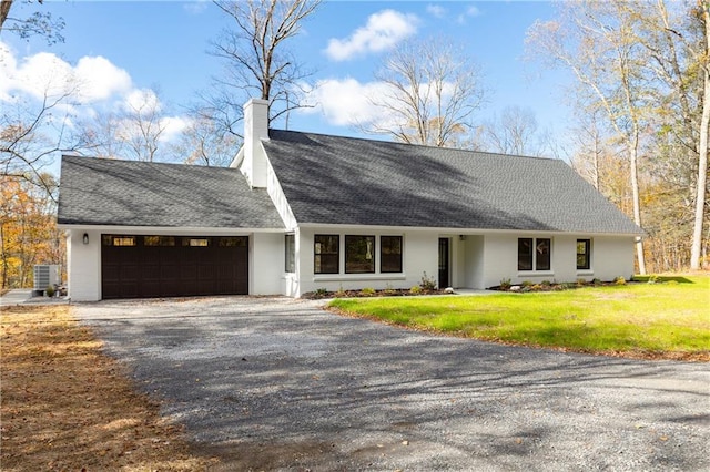 view of front of house featuring a garage, driveway, roof with shingles, a front lawn, and a chimney