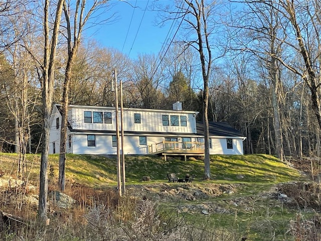 view of front of property featuring a chimney, a front lawn, and a wooden deck