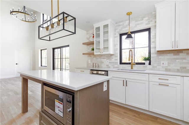 kitchen featuring stainless steel appliances, light countertops, light wood-style floors, a sink, and plenty of natural light