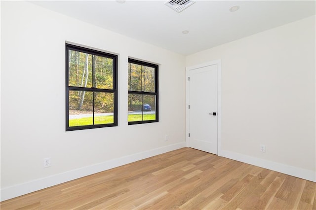 empty room featuring light wood-style floors, visible vents, and baseboards