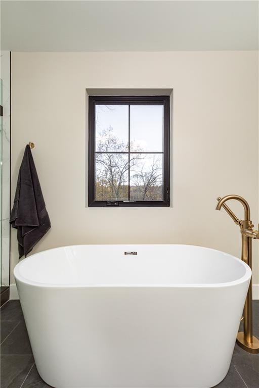 bathroom with a soaking tub and tile patterned floors