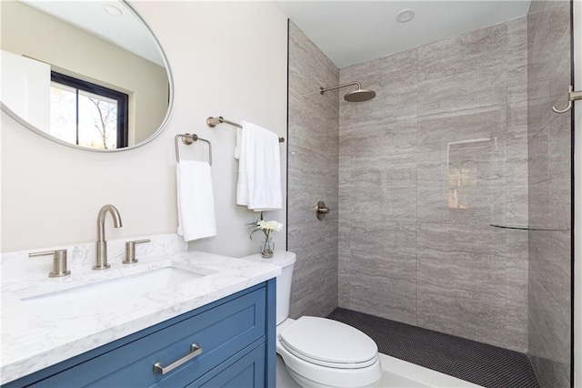 bathroom featuring tiled shower, vanity, and toilet