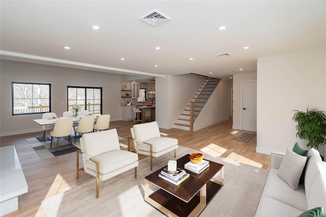 living room featuring light wood finished floors, recessed lighting, visible vents, baseboards, and stairs