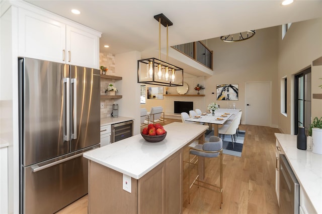 kitchen featuring a kitchen island, wine cooler, freestanding refrigerator, white cabinetry, and open shelves