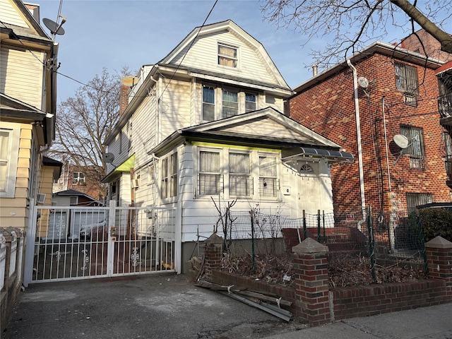 view of front of property with a gate, fence, and a gambrel roof