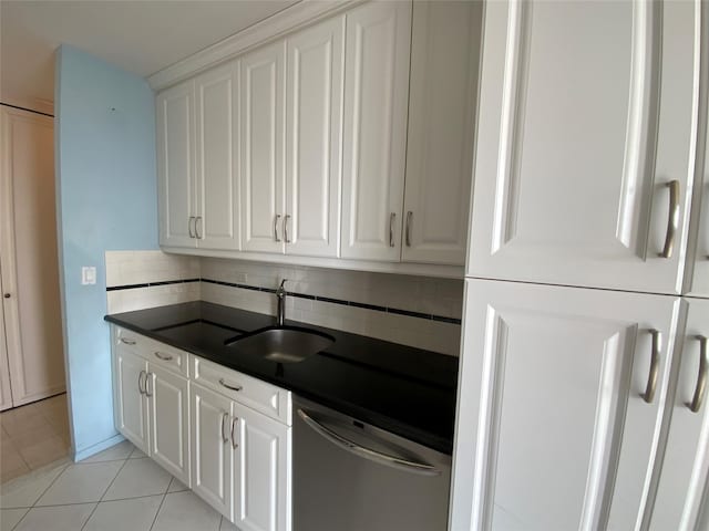 kitchen with dark countertops, white cabinetry, a sink, and stainless steel dishwasher