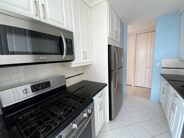 kitchen featuring light tile patterned floors, white cabinets, appliances with stainless steel finishes, tasteful backsplash, and dark countertops