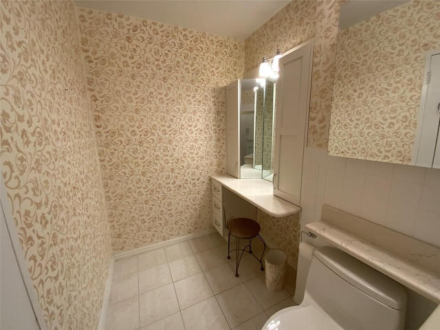 bathroom featuring tile patterned flooring, baseboards, toilet, and wallpapered walls