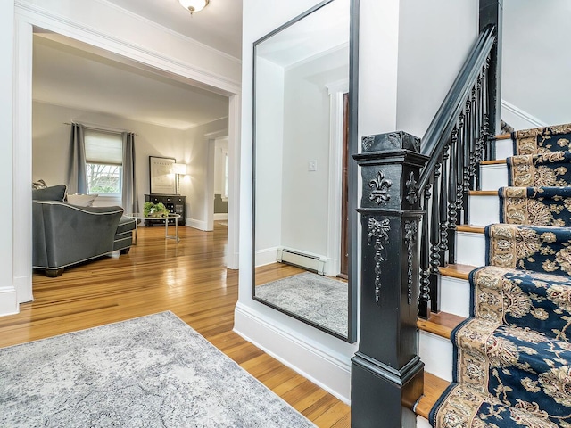 stairs featuring a baseboard heating unit, wood finished floors, and baseboards