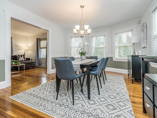 dining area featuring a chandelier, wood finished floors, and baseboards