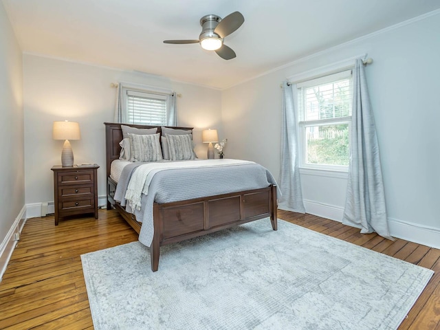 bedroom with hardwood / wood-style flooring, ceiling fan, baseboards, and crown molding