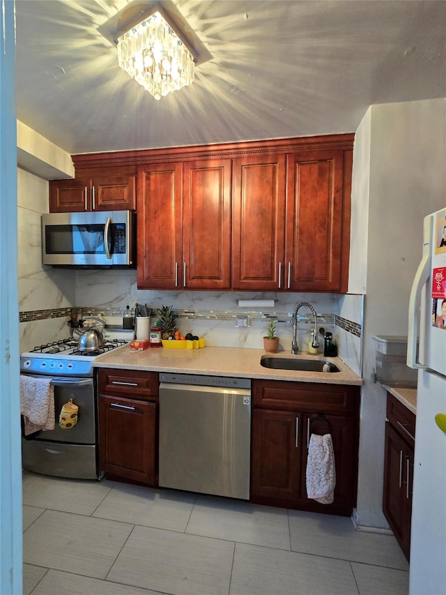 kitchen featuring stainless steel appliances, a sink, light countertops, and decorative backsplash