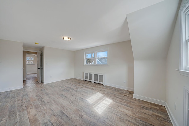 empty room featuring radiator heating unit, wood finished floors, and baseboards