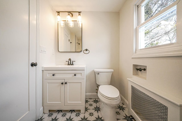 bathroom with toilet, vanity, baseboards, tile patterned floors, and radiator