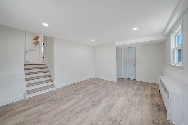 empty room with stairs, recessed lighting, light wood-style flooring, and radiator