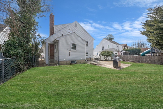 back of house featuring a patio, a chimney, a fenced backyard, and a lawn