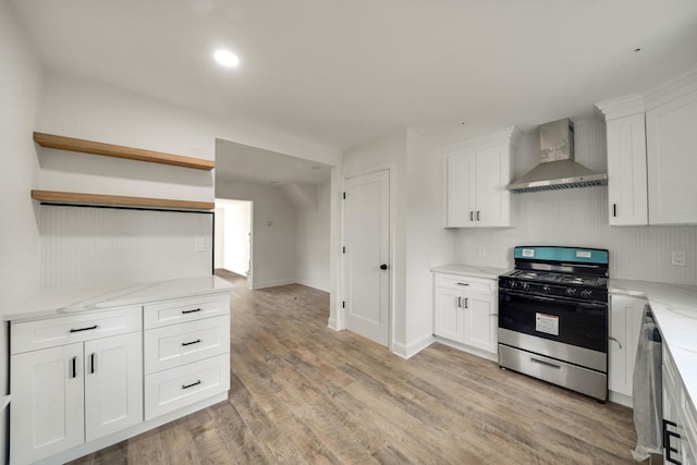 kitchen featuring white cabinets, light wood-type flooring, backsplash, wall chimney exhaust hood, and gas stove