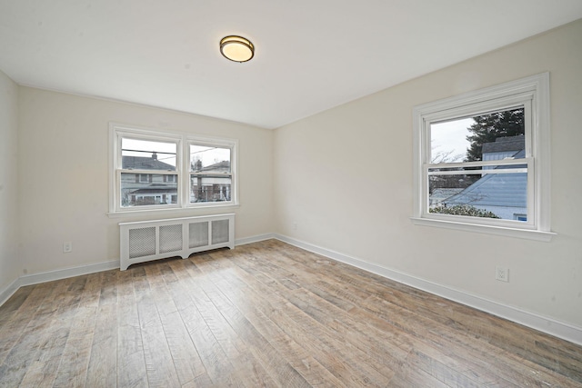 empty room with baseboards, hardwood / wood-style floors, and radiator