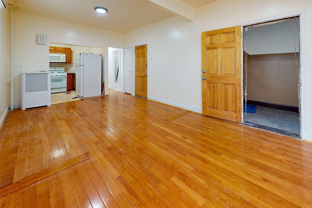 unfurnished room featuring light wood-style floors, beam ceiling, and baseboards