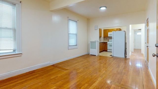 interior space featuring beamed ceiling, light wood-type flooring, and baseboards