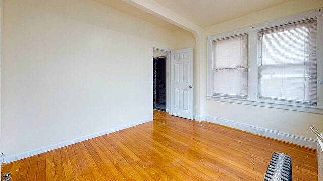 spare room with light wood-style floors, baseboards, and radiator heating unit