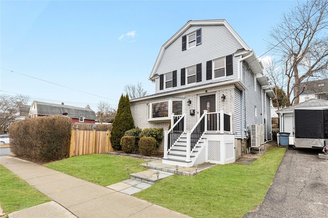 dutch colonial with a front yard, fence, and a gambrel roof