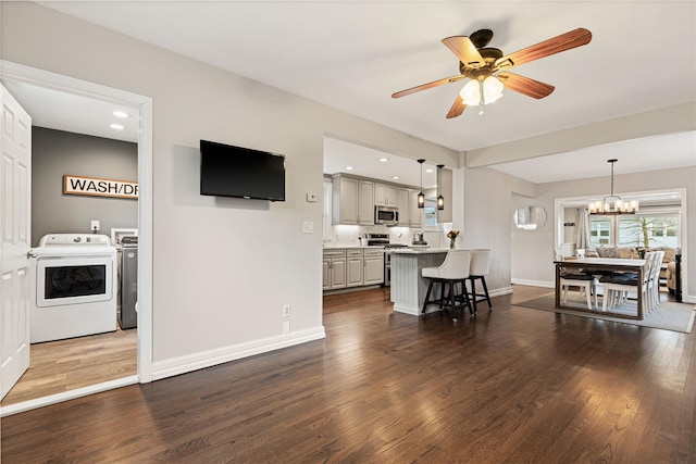 living room featuring ceiling fan with notable chandelier, washer and dryer, dark wood finished floors, recessed lighting, and baseboards