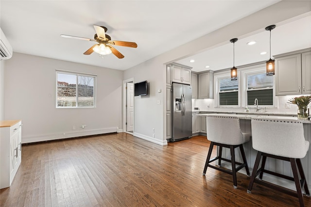 kitchen featuring hardwood / wood-style floors, a baseboard radiator, stainless steel fridge with ice dispenser, gray cabinetry, and decorative backsplash