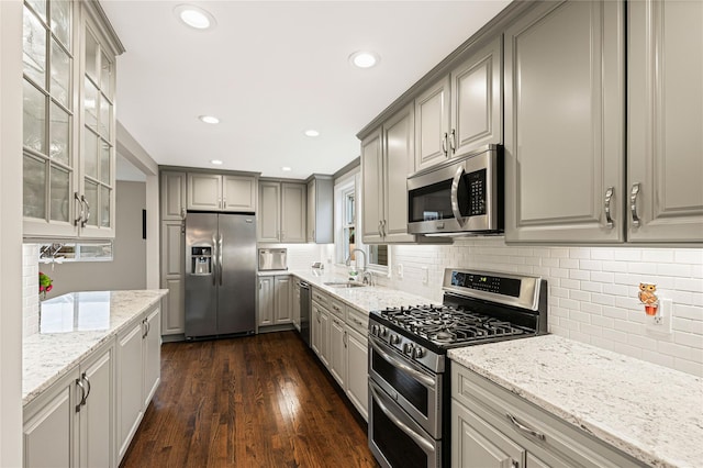 kitchen with a sink, stainless steel appliances, glass insert cabinets, and gray cabinets