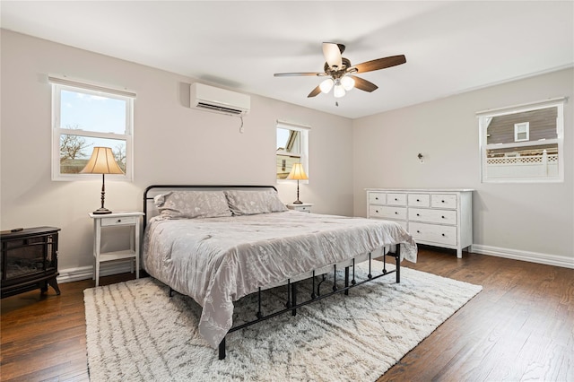 bedroom featuring ceiling fan, an AC wall unit, baseboards, and hardwood / wood-style floors