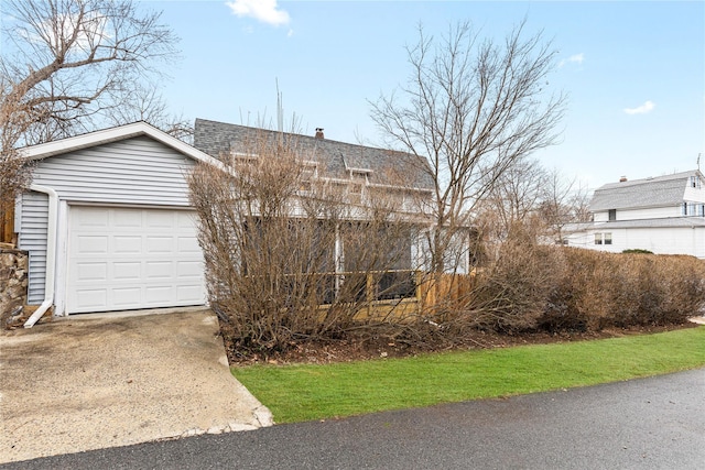 view of front of house featuring concrete driveway, a garage, roof with shingles, and a chimney