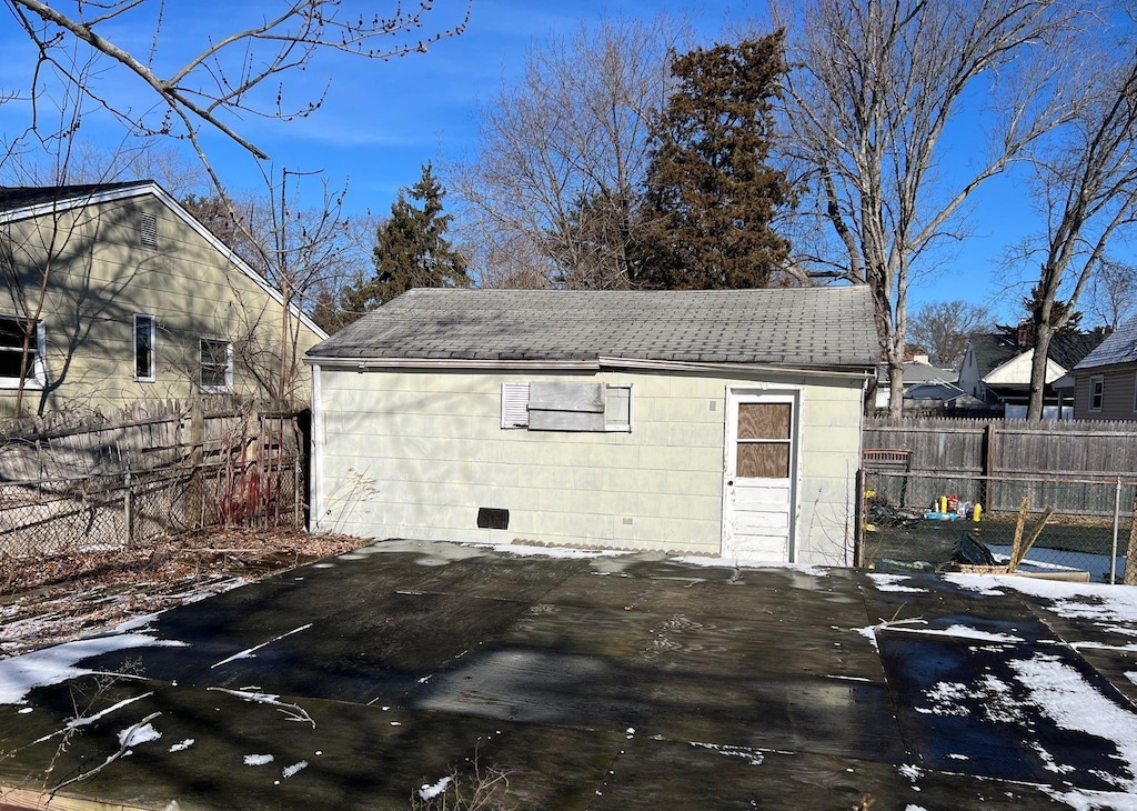 snow covered structure with fence and an outbuilding