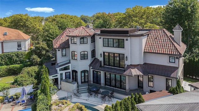 mediterranean / spanish home with stucco siding, entry steps, a patio area, fence, and a tiled roof