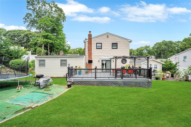 back of property featuring a deck, a trampoline, a lawn, and a pergola