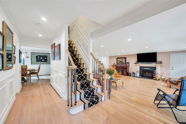 hallway with recessed lighting, a decorative wall, stairway, and light wood finished floors