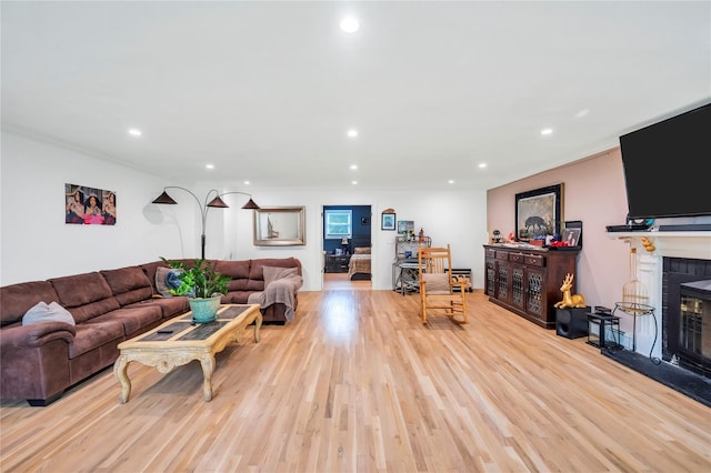 living area featuring ornamental molding, light wood finished floors, a brick fireplace, and recessed lighting