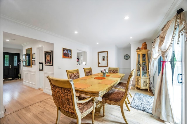 dining area with a wainscoted wall, light wood-style flooring, ornamental molding, and recessed lighting