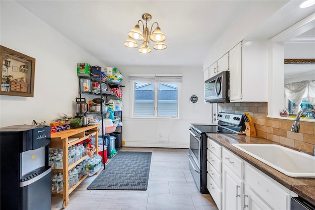 kitchen with appliances with stainless steel finishes, dark countertops, white cabinets, and a sink