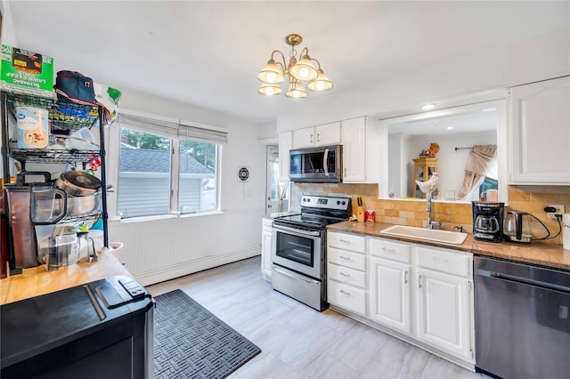 kitchen with white cabinets, baseboard heating, stainless steel appliances, and a sink