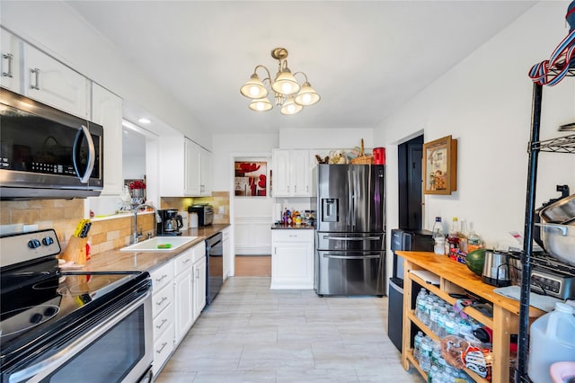 kitchen featuring a notable chandelier, stainless steel appliances, a sink, and white cabinets