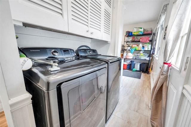 laundry area with cabinet space, separate washer and dryer, and light wood-style floors