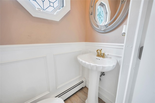 half bath featuring a baseboard heating unit and wainscoting