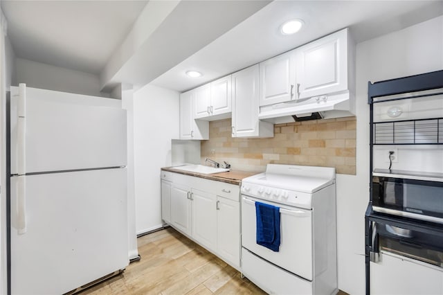 kitchen featuring white appliances, white cabinets, light countertops, under cabinet range hood, and a sink